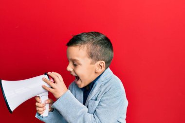 Sevimli beyaz çocuk kırmızı arka plan üzerinde megafon kullanarak çığlık atıyor..