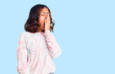 Kravat boyası kazak giyen genç ve güzel bir ırk kadını ağzıyla esnemekten sıkılmış. Huzursuz ve uykulu.. 