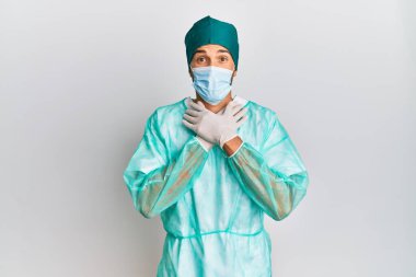 Cerrah üniforması ve tıbbi maske takan genç yakışıklı adam bağırıyor ve boğuluyor çünkü acı verici bir boğulma var. Sağlık problemi. Boğulma ve intihar konsepti. 