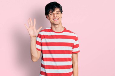 Yakışıklı hippi genç adam, sıradan çizgili tişört giyiyor. Beş numarayı gösteriyor ve gülümsüyor. Kendinden emin ve mutlu.. 