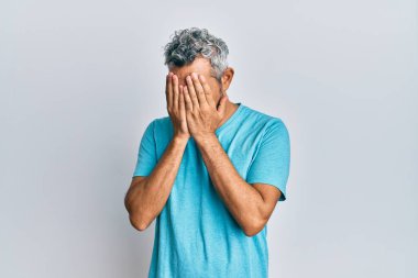 Orta yaşlı, gri saçlı, günlük kıyafetler giyen, suratını ellerle örten ve ağlayan bir adam. depresyon kavramı. 