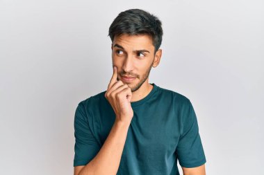 Genç, yakışıklı, günlük kıyafetler giyen, şüpheye odaklanmış, çenesinde parmak olan ve kafasını kaldırıp merak eden biri. 