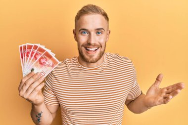 Kafkasyalı genç adam elinde 20 İsrail şekeri olan banknotlar başarıyı mutlu bir gülümsemeyle ve kazanan ifadeyle el kaldırarak kutluyor. 