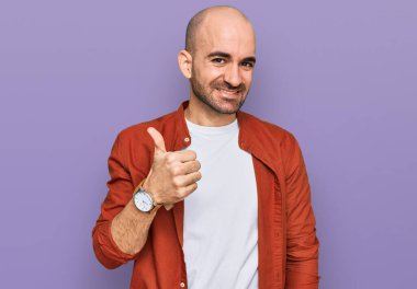 Gündelik kıyafetler giyen genç İspanyol adam elleriyle mutlu bir jest yapıyor. Kameraya bakıp başarıyı gösteren ifade. 