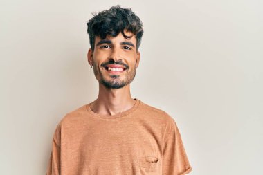 Yüzünde mutlu ve havalı bir gülümseme olan sıradan kıyafetler giyen genç İspanyol bir adam. şanslı kişi. 