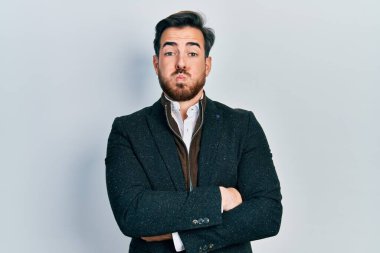 Kollarını kavuşturmuş, sakallı yakışıklı beyaz adam komik suratlı, yanakları şişiren adam. Ağzı havayla şişer, havayı yakalar.. 