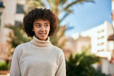 Genç İspanyol kız gülümseyerek şehirde mutlu mesut dikiliyor..