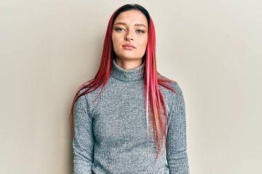 Gündelik kıyafetler giyen beyaz bir kadın. Yüzünde ciddi bir ifadeyle rahatlamış. Basit ve doğal bir şekilde kameraya bakıyorsun.. 