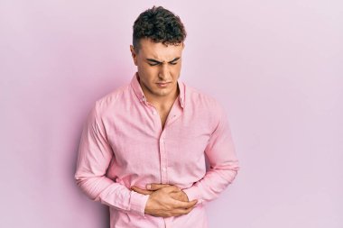 Hispanik genç adam elleri karnında günlük kıyafetler giyiyor çünkü hazımsızlık, acı verici bir hastalık kendini iyi hissetmiyor. Ağrı kavramı. 