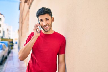 Genç Latin adam gülümsüyor. Şehirdeki akıllı telefondan konuşuyor..
