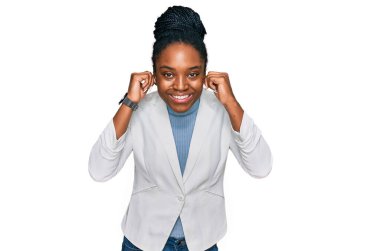 Genç Afro-Amerikan kadın iş kıyafetleri içinde gülümsüyor kulaklarını parmaklarıyla çekiyor, komik bir jest. deneme sorunu 