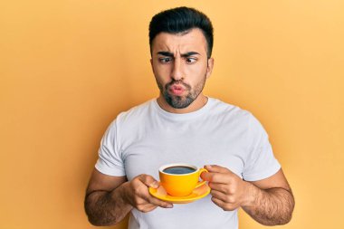 Genç İspanyol bir adam bir fincan kahve içiyor ağzıyla balık suratı yapıyor ve şaşı bakıyor, çılgın ve komik.. 