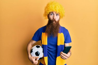 Kızıl saçlı, uzun sakallı futbol holigan tezahürat oyunu elinde akıllı telefon ağzıyla balık suratlı ve şaşı gözlü çılgın ve komik gözlü.. 