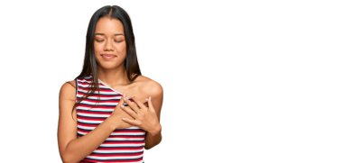 Güzel İspanyol kadın gündelik giysiler giyiyor. Elleri göğsünde, gözleri kapalı gülümsüyor ve yüzünde minnet ifadesi var. sağlık kavramı. 