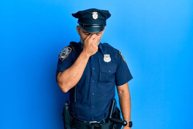 Orta yaşlı, yakışıklı, polis üniforması giyen, burnu ve gözleri ovuşturmaktan yorgun, yorgun ve başı ağrıyor. Stres ve hüsran kavramı. 