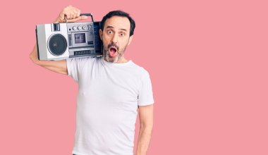 Orta yaşlı yakışıklı adam müzik dinliyor. Klasik müzik aleti kullanıyor. Korkmuş ve ağzı açık bir şekilde şaşırmış. 