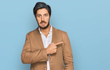 İş kıyafetleri giymiş genç İspanyol bir adam endişeli ve endişeli bir ifade takınıyor. 