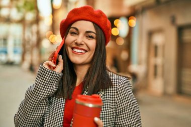 Genç İspanyol kadın akıllı telefondan konuşuyor ve şehirde kahve içiyor..