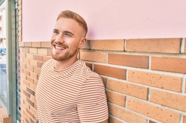 Genç İrlandalı gülümseyen mutlu adam şehrin duvarına yaslanıyor..