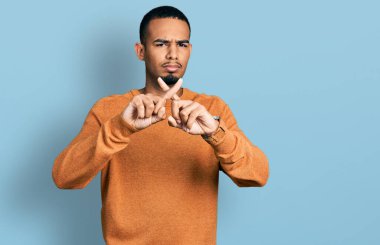 Genç Afro-Amerikalı, günlük kıyafetler giymiş, reddedilmiş yüz ifadesi. Eksi işareti yapıyor. 