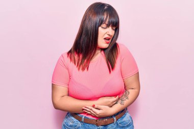 Genç ve cüsseli bir kadın elleri karnında günlük kıyafetler giyiyor çünkü mide bulantısı, acı verici bir hastalık kendini iyi hissetmiyor. Ağrı kavramı. 