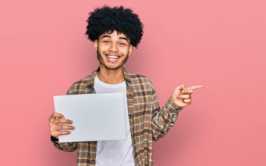 Afro saçlı, boş afiş taşıyan, mutlu gülümseyen, eli ve parmağı yanda olan Afro Amerikalı genç bir adam. 
