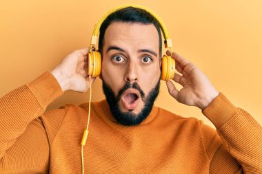 Sakallı genç adam kulaklık takarak müzik dinliyor. Şaşırmış, korkmuş, şaşkınlık içinde bir ifade, korku ve heyecanlı bir yüz.. 