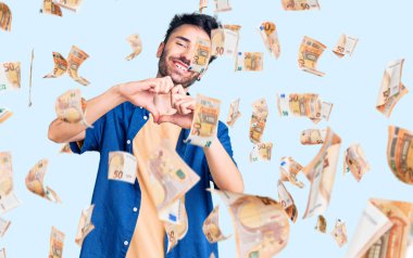 Gündelik kıyafetler giyen, aşık gülümseyen, elleriyle kalp sembolü yapan genç bir İspanyol. romantik kavram.