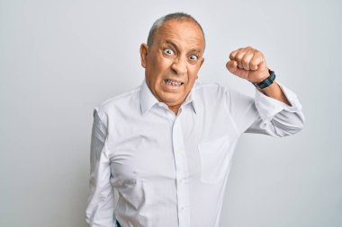 Yakışıklı, beyaz gömlek giyen, sinirli, kızgın, yumruğunu kaldıran sinirli ve öfkeyle bağıran bir adam. öfke ve agresif konsept. 