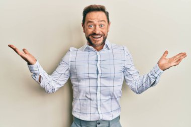 Orta yaşlı bir adam iş kıyafetleri içinde zaferi kutlarken mutlu bir gülümseme ve ellerini kaldırarak kazanan bir ifade takındı. 