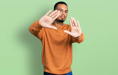 Genç Afro-Amerikalı günlük kıyafetler giyen, el ve parmaklarıyla çerçeve yapan, kamera perspektifli bir adam. 