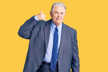 İş ceketi giyen yaşlı gri saçlı adam telefonla el ve parmak hareketleriyle gülümsüyor telefonda konuşuyor gibi. iletişim kavramları. 