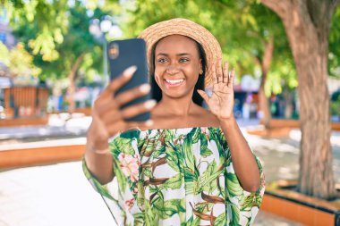 Genç Afro-Amerikan turist kadın tatilde gülümseyerek şehirde akıllı telefon kullanarak video araması yapıyor..