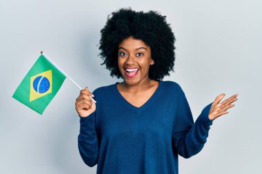 Genç Afrikalı Amerikalı kadın Brezilya bayrağını tutarak zaferi mutlu bir gülümsemeyle ve kazanan ifadeyle kutluyor. 