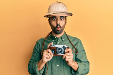 Kaşif şapkası ve klasik kamera takan genç İspanyol adam ağzı ve şaşı gözleriyle balık suratı yapıyor, çılgın ve komik.. 