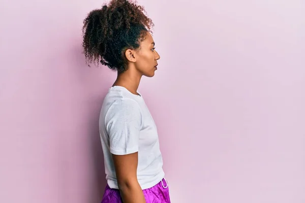 Beautiful african american woman with afro hair wearing sportswear looking to side, relax profile pose with natural face with confident smile.