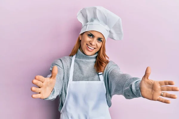 身穿职业厨师制服 头戴帽子的西班牙裔年轻女性看着摄像机 张开双臂拥抱对方 欢快的表达拥抱幸福 — 图库照片