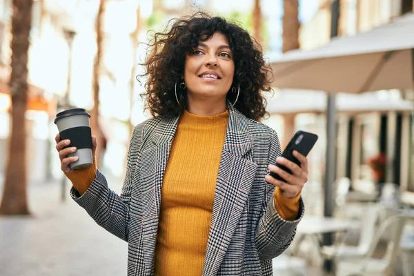 Genç İspanyol iş kadını akıllı telefon kullanıyor. Şehirde kahve içiyor..