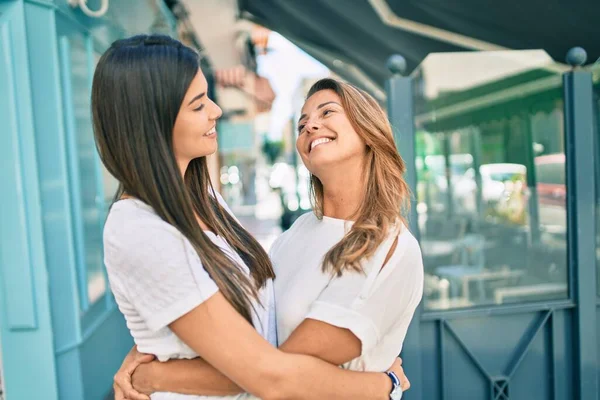 Güzel İspanyol anne ve kızı gülümseyerek şehirde mutlu mesut duruyorlar..