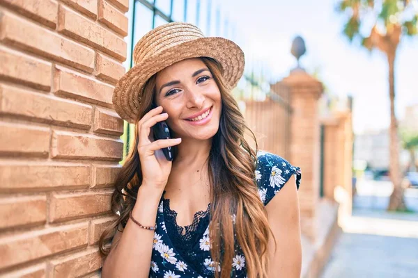 Young hispanic woman on vacation talking on the smartphone at street of city.