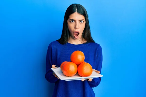 Mujer Hispana Joven Sosteniendo Plato Con Naranjas Frescas Cara Choque —  Fotos de Stock