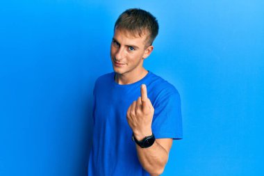 Genç, beyaz, sıradan mavi tişörtlü bir adam seni buraya davet ediyor. Bir jest yap, mutlu bir şekilde karşıla ve gülümse. 