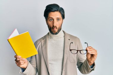Genç İspanyol bir adam kitap okuyor ve gözlük tutuyor. Ağızla balık yüzü yapıyor ve şaşı bakıyor. Deli ve komik.. 