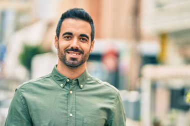 Genç İspanyol adam gülümseyerek şehirde mutlu mesut dikiliyor..