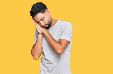 Sakallı genç adam, günlük gri tişört giyer, uyur, yorgun düşler kurar, elleriyle poz verir ve gözleri kapalı gülümserdi.. 