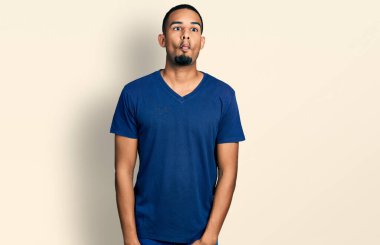 Gündelik tişört giyen genç Afro-Amerikan adam dudaklarıyla balık suratı yapıyor, çılgınca ve komik bir jest. Komik ifade. 