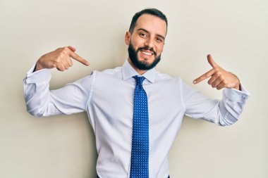 Sakallı, iş kravatlı, kendine güvenen, gülümseyen, kendini gururlu ve mutlu gösteren genç bir adam.. 