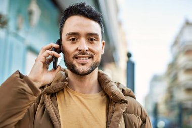 Genç İspanyol adam gülümsüyor. Şehirdeki akıllı telefondan konuşuyor..