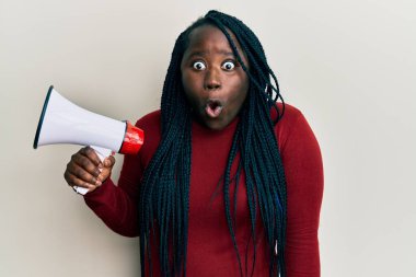 Örgülü genç zenci kadın megafonla bağırıyor. Şaşırmak için ağzı açık kalmış, korkmuş ve hayrete düşmüş. İnanmayan yüz. 