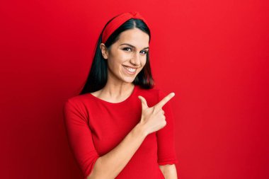 Genç İspanyol kadın gündelik giysiler giyiyor. Gülümsüyor, elleri ve parmakları yana doğru işaret ediyor. 